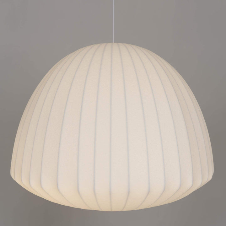 Dome-shaped Nelson Bubble pendant light with a softly illuminated white ribbed shade on a gray background