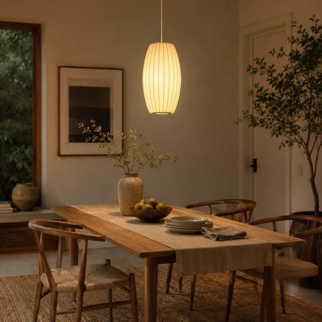 Elongated oval Nelson Bubble pendant light above a wood dining table in a warm contemporary dining room