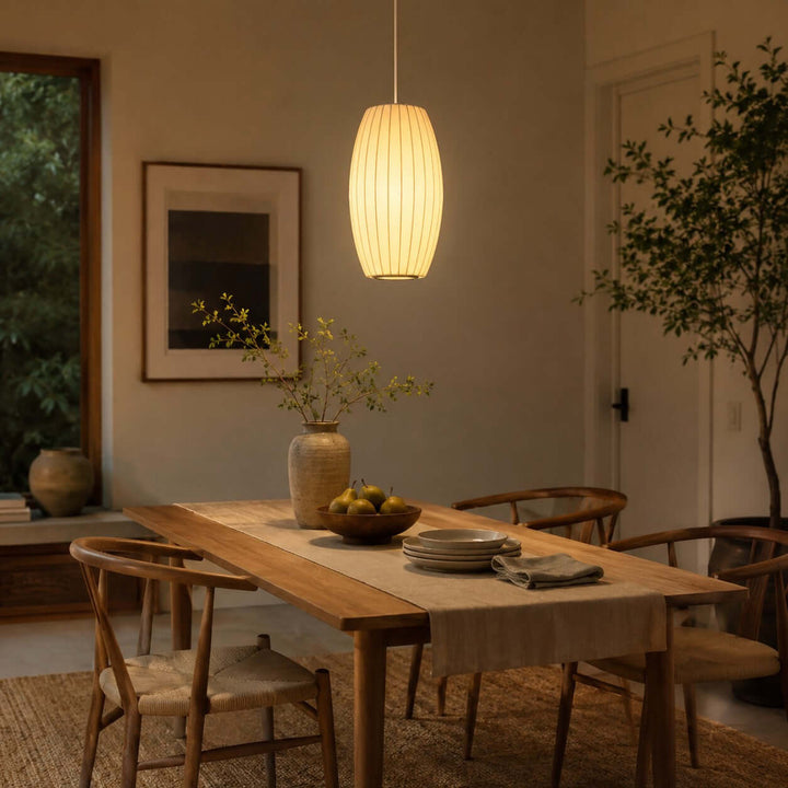 Elongated oval Nelson Bubble pendant light above a wood dining table in a warm contemporary dining room
