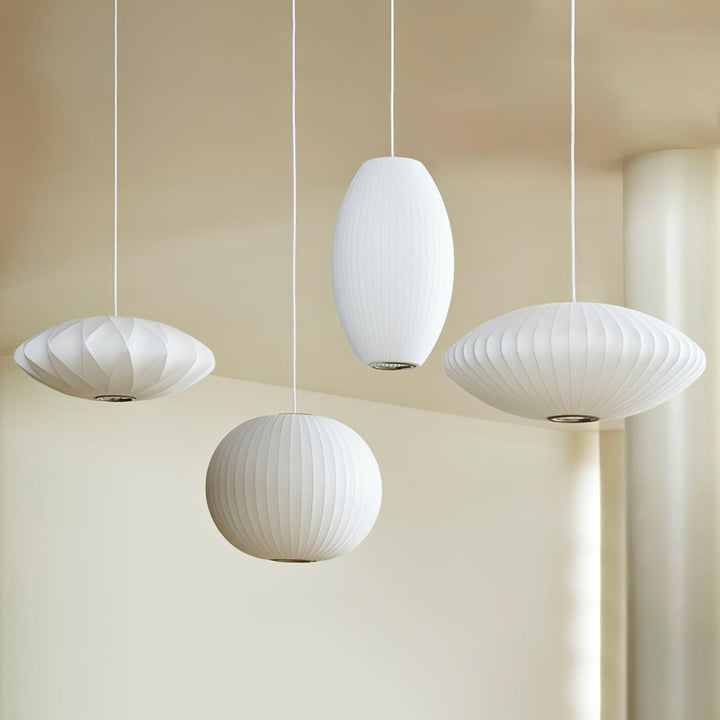 Four white Nelson Bubble pendant lamps in saucer, globe and oval shapes displayed in a modern interior