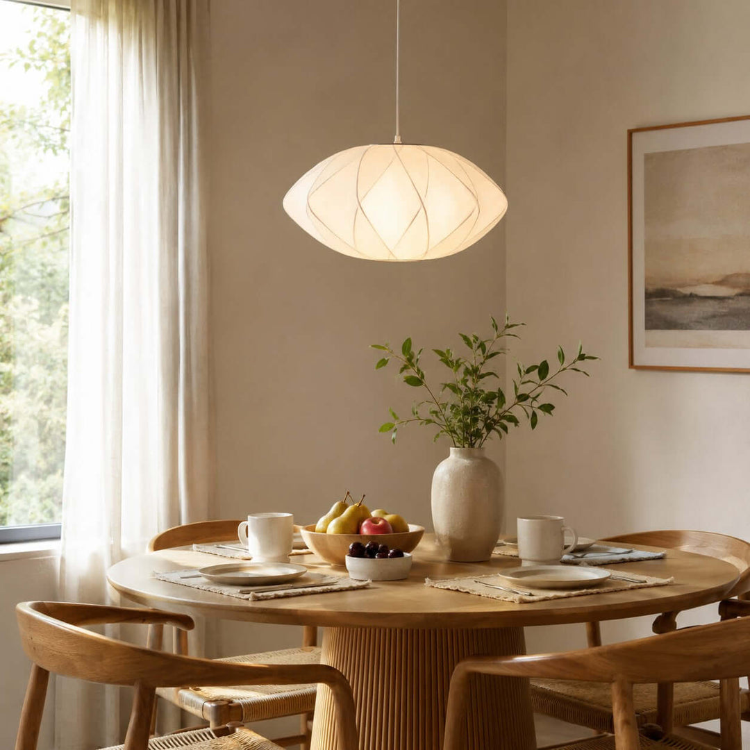Nelson Bubble pendant lamp with a geometric silk shade above a round wood dining table beside a sunlit window