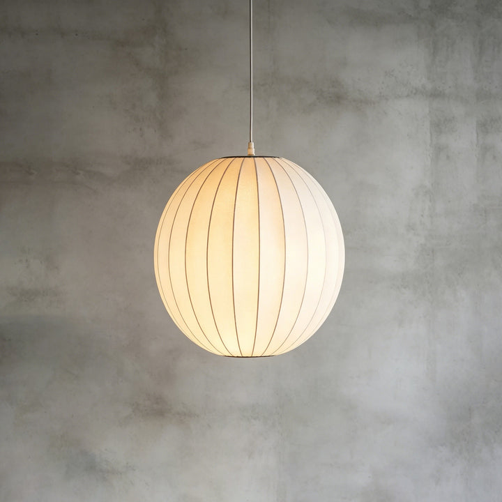 Globe-shaped Nelson Bubble pendant light with a softly glowing white silk shade on a concrete backdrop