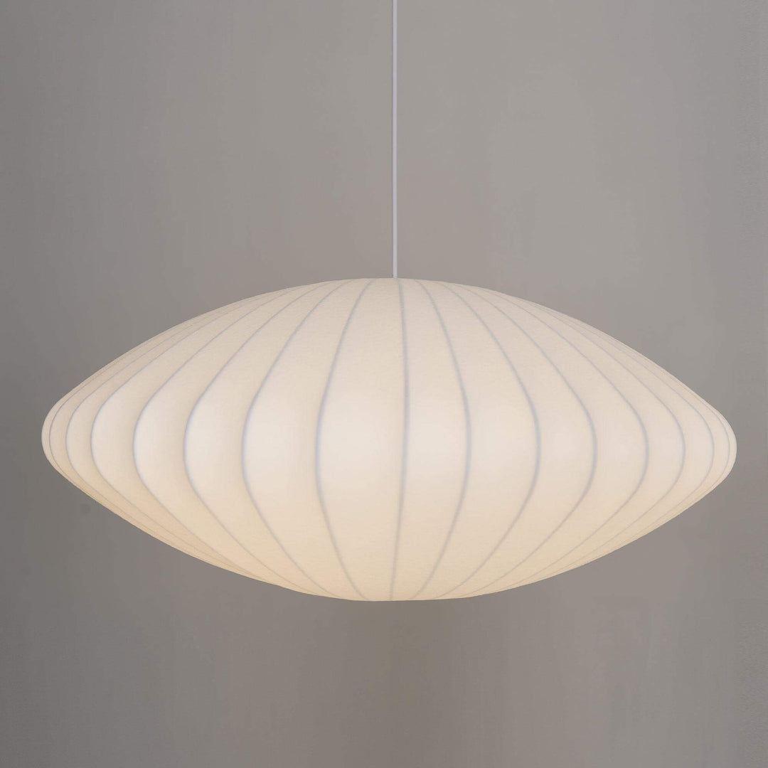 White saucer-shaped Nelson Bubble pendant lamp softly illuminated against a clean gray background