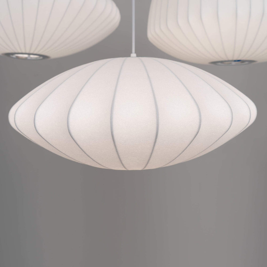 Close view of a white Nelson Bubble saucer pendant with ribbed silk texture and a rounded profile