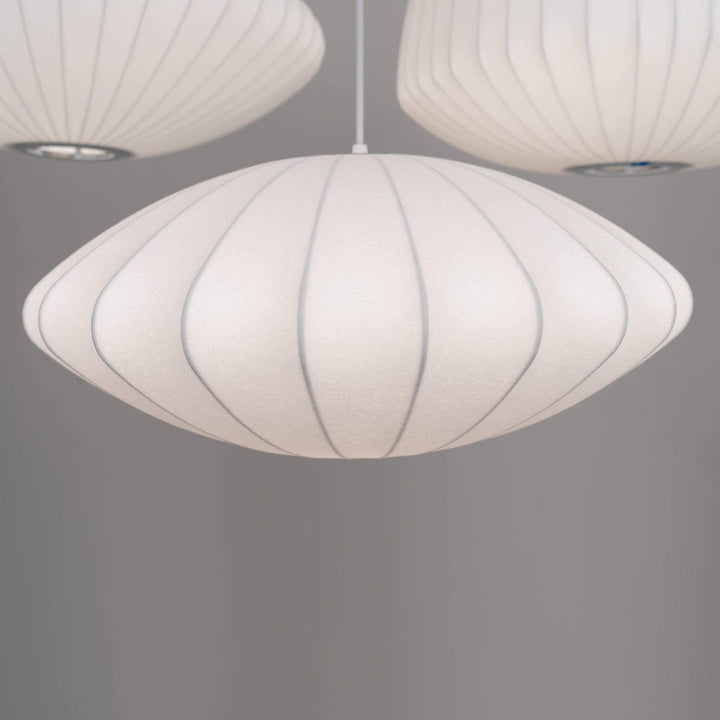 Close view of a white Nelson Bubble saucer pendant with ribbed silk texture and a rounded profile