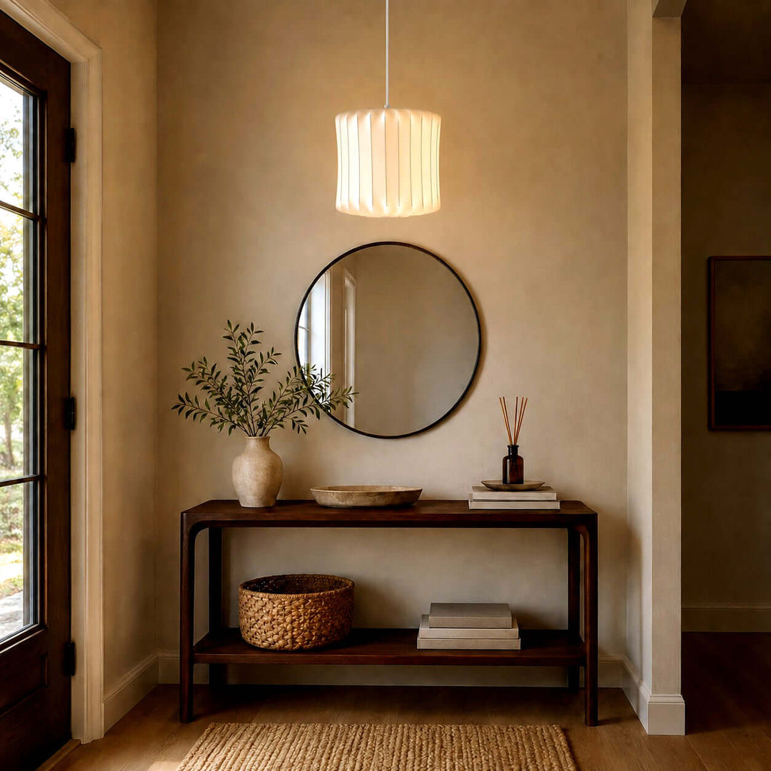 Wavy cylindrical Nelson Bubble pendant lamp above a wood console and round mirror in a warm entryway
