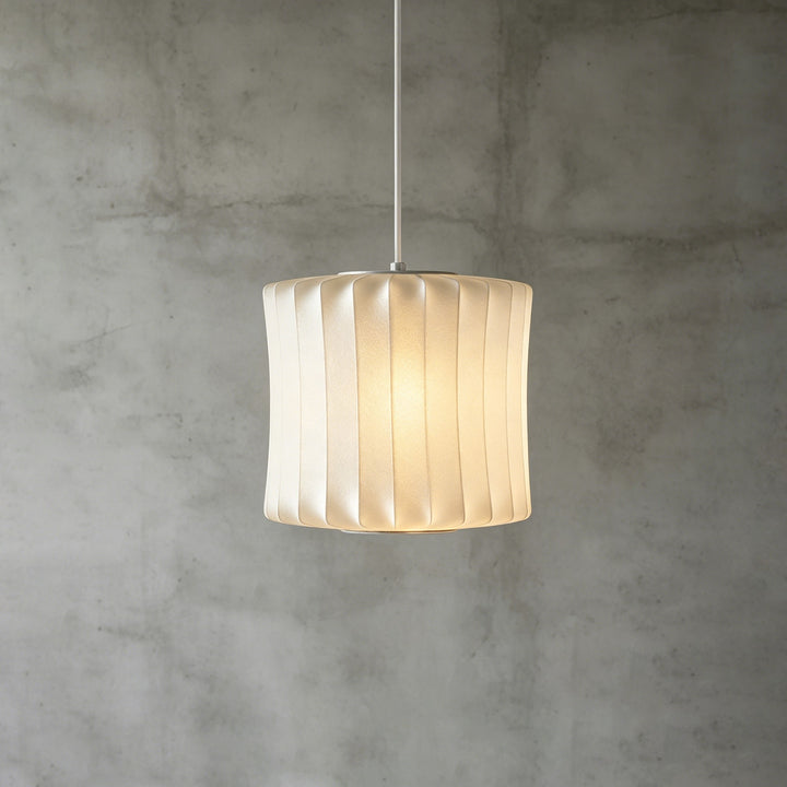 Wavy cylindrical Nelson Bubble pendant light with folded white silk panels against a concrete background
