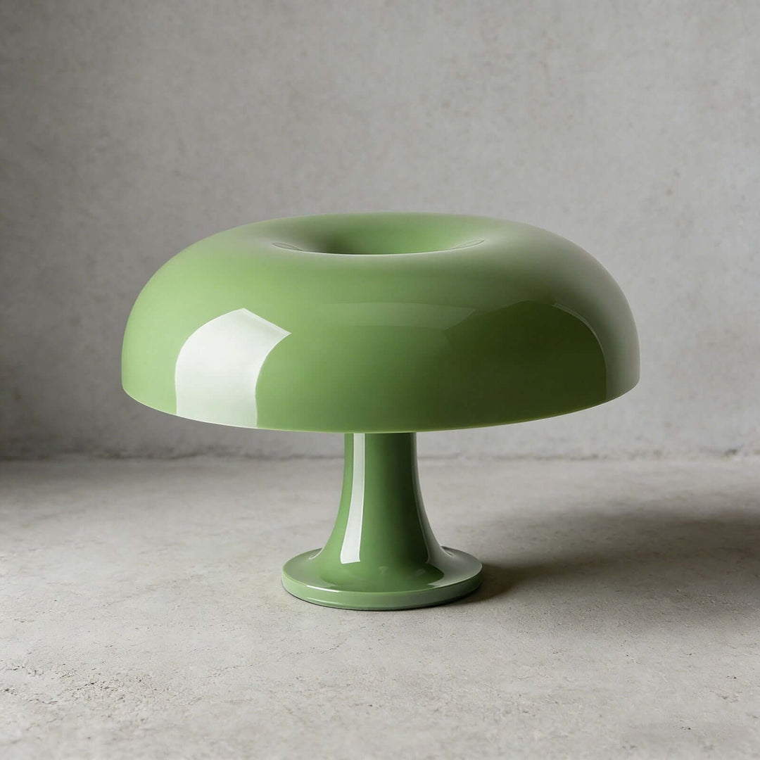 Green Nesso Table Lamp with a mushroom-shaped dome on a concrete surface