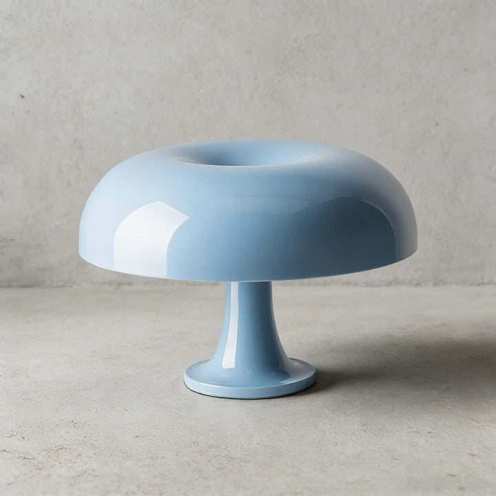 Light blue Nesso Table Lamp with a glossy finish against a concrete background
