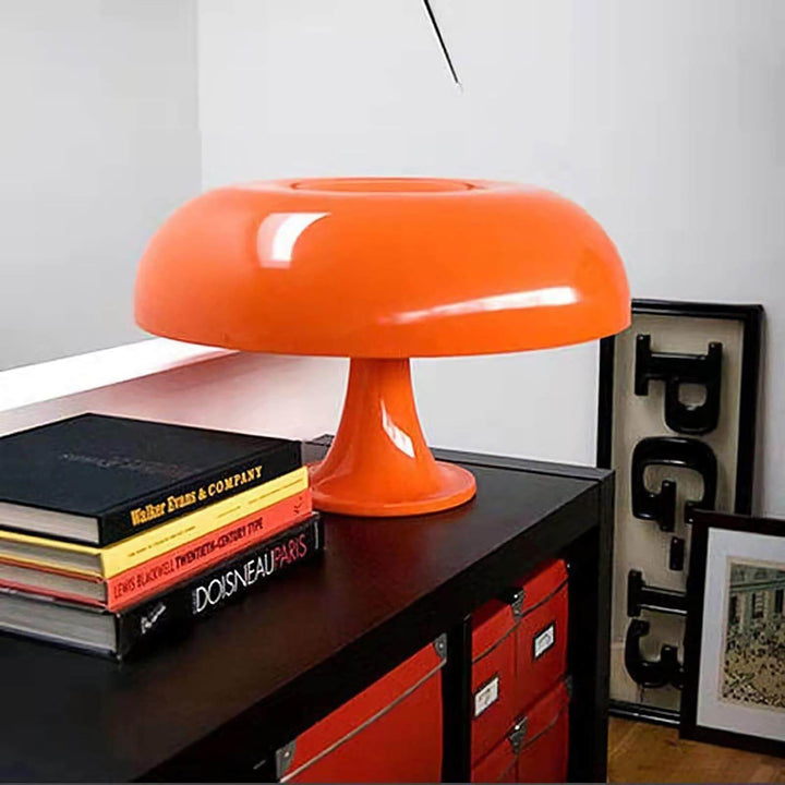 Close view of the orange Nesso Table Lamp displayed with stacked design books