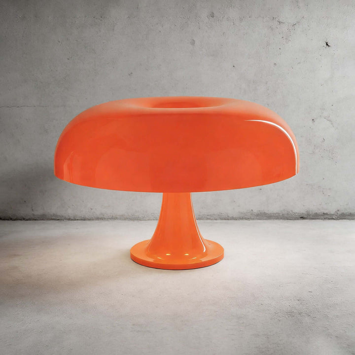 Orange Nesso Table Lamp with a glossy dome shade against a gray concrete background