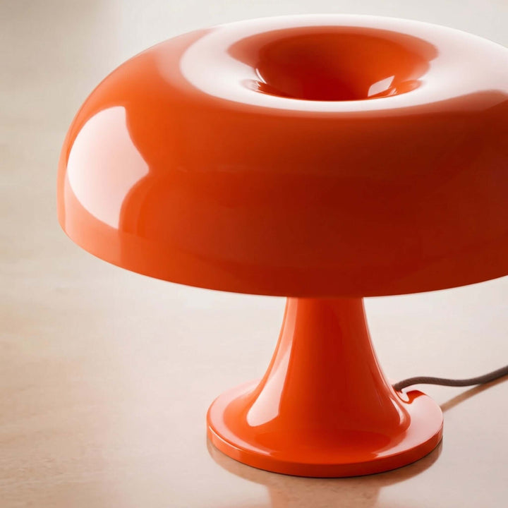 Close-up of the orange Nesso Table Lamp with a glossy acrylic dome and pedestal base