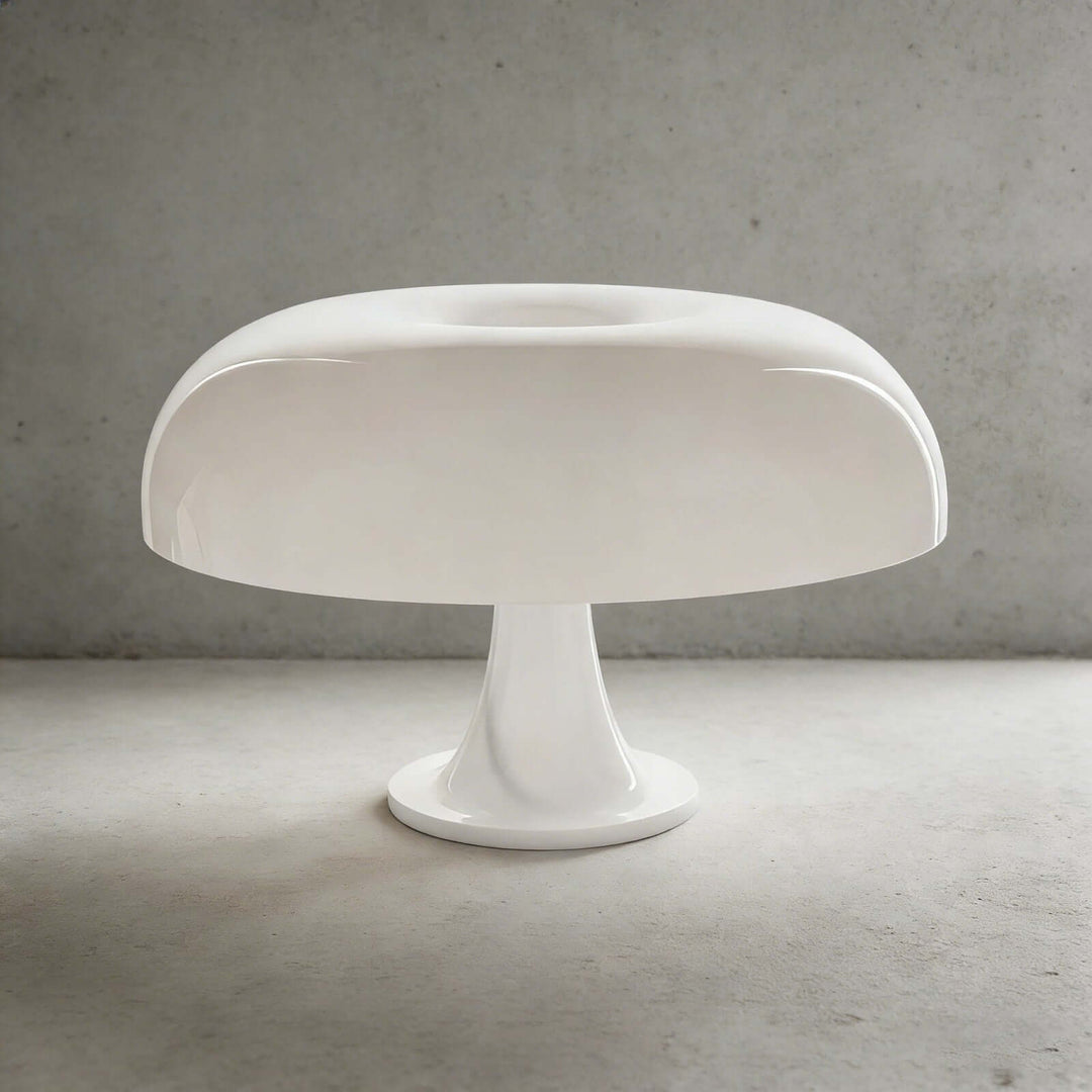 White Nesso Table Lamp with a sculpted dome shade against a gray concrete background