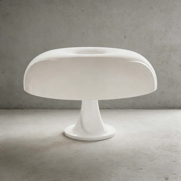 White Nesso Table Lamp with a sculpted dome shade against a gray concrete background