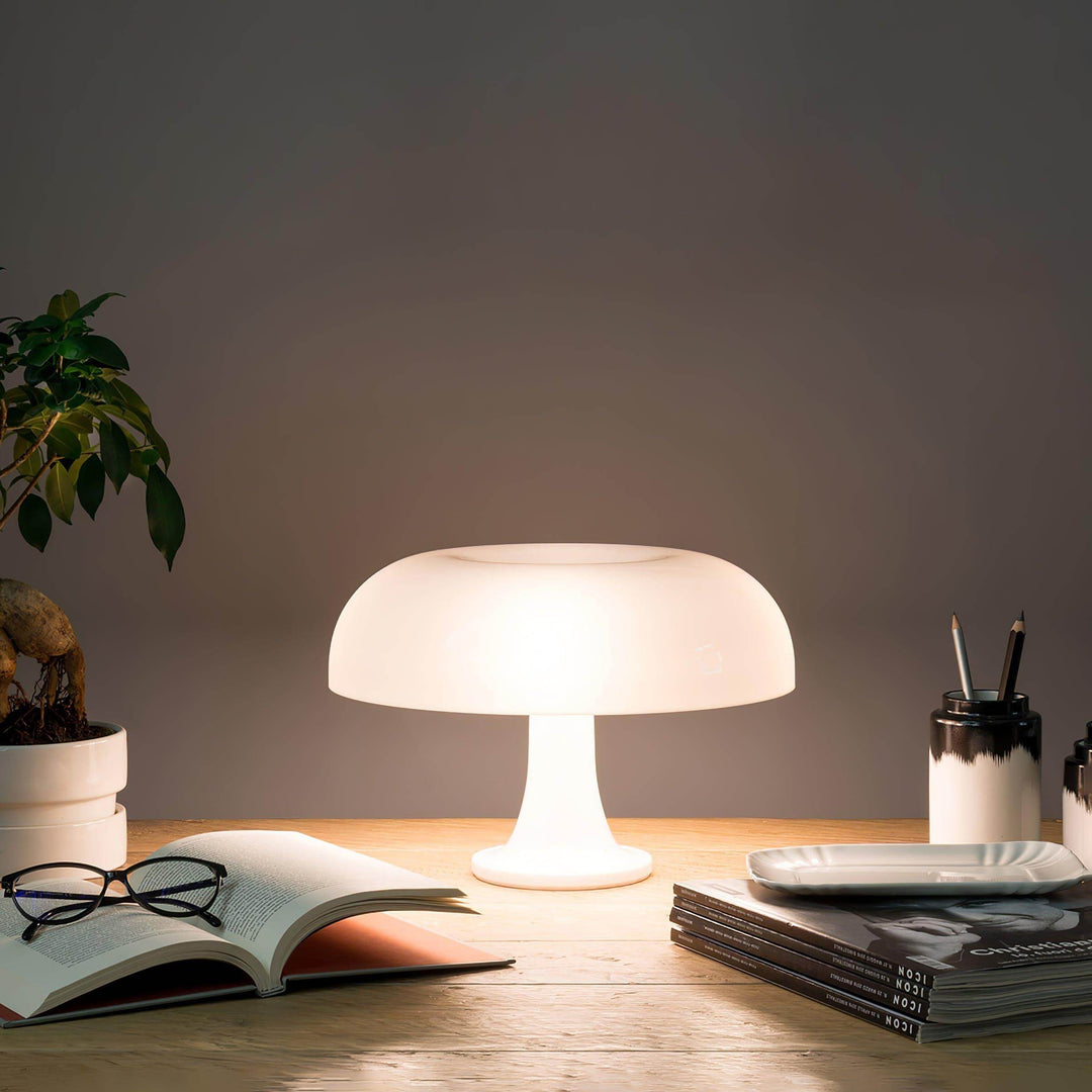 White Nesso Table Lamp illuminating an open book and reading glasses on a desk
