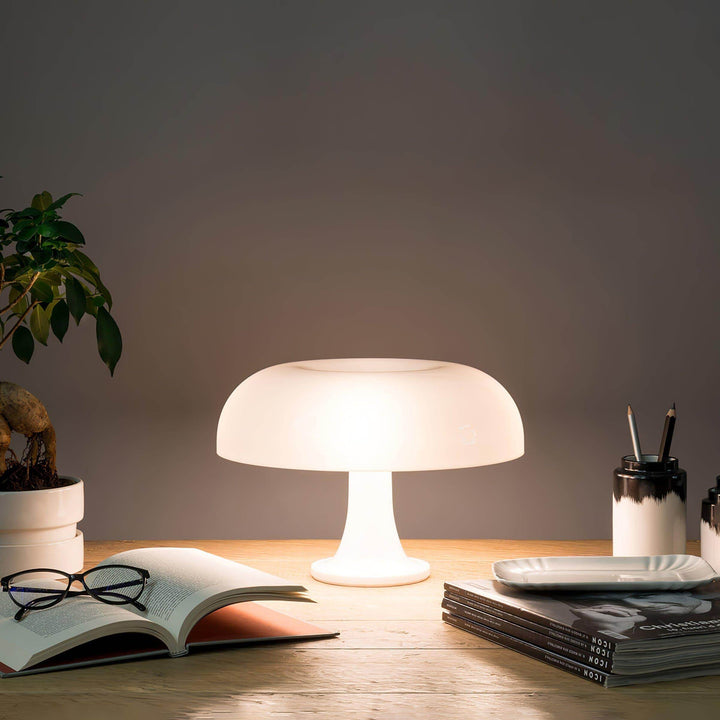 White Nesso Table Lamp illuminating an open book and reading glasses on a desk
