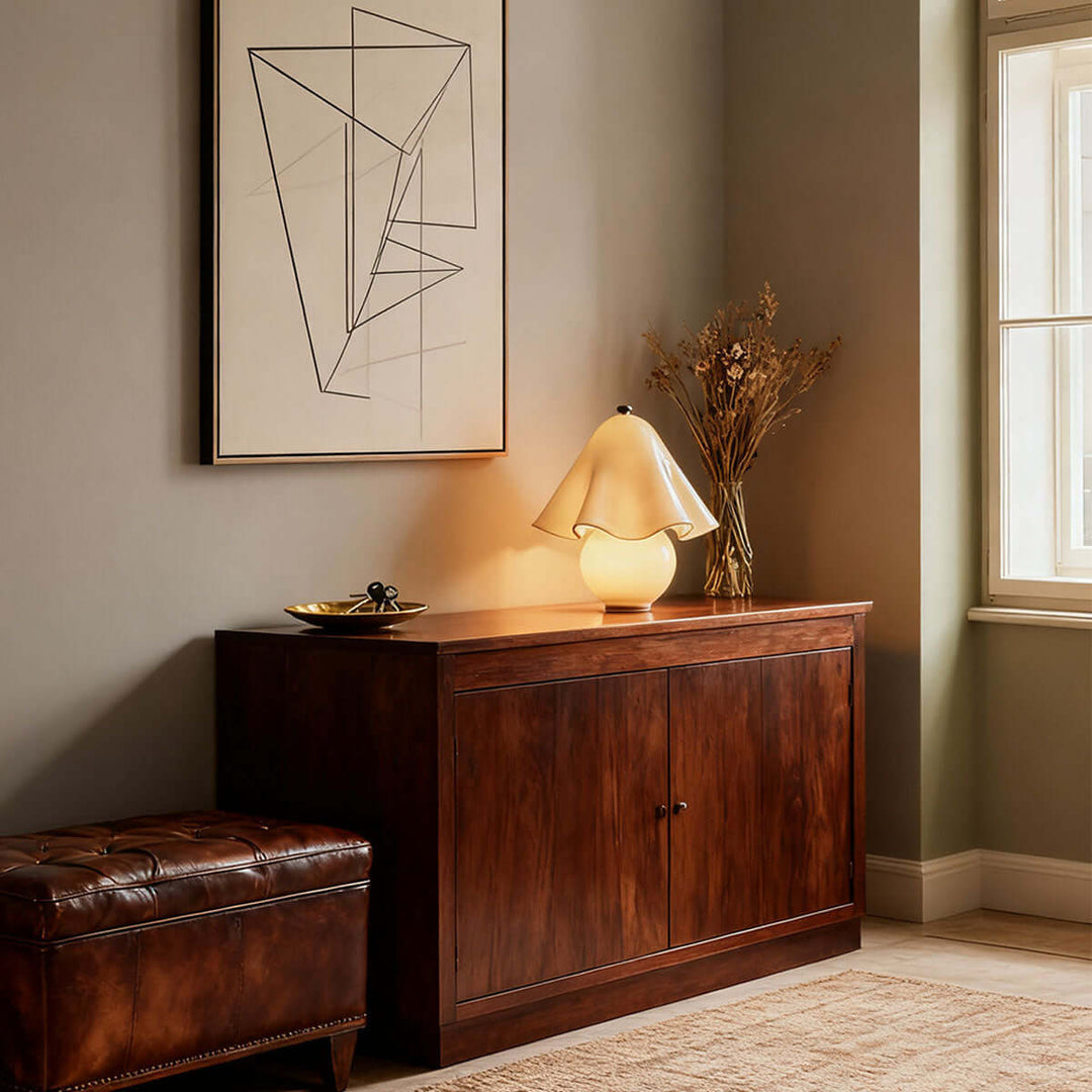 Frosted amber flower table lamp on a dark wood living room console below modern artwork