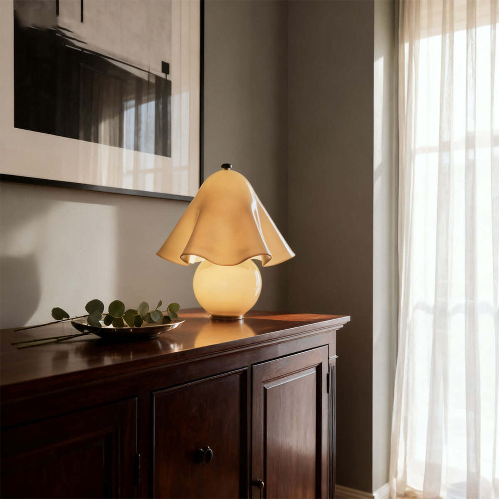 Frosted amber glass table lamp glowing warmly on a dark wood console cabinet