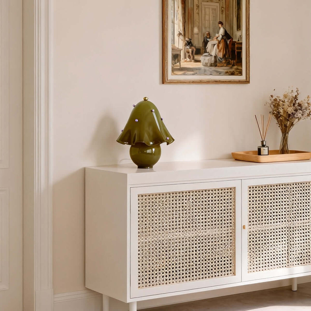 Spotted green glass table lamp on a white cane-front entryway console