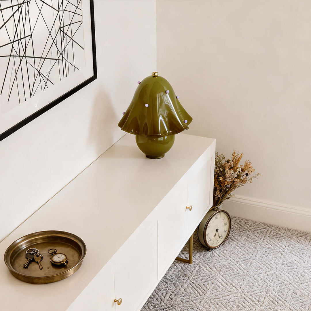 Spotted green flower table lamp on a white sideboard with vintage accessories
