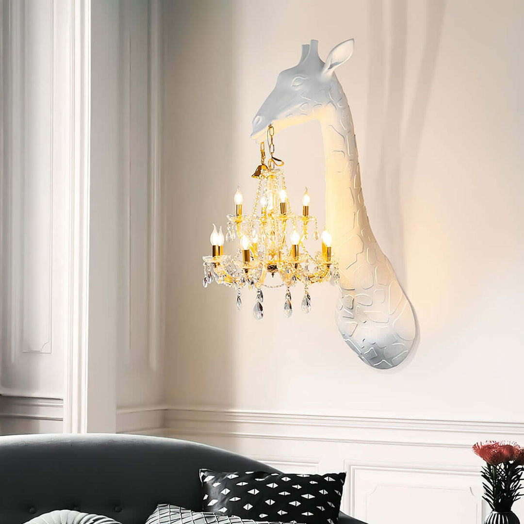 White Nuvexa giraffe wall lamp holding a gold crystal chandelier above a dark sofa in an elegant living room
