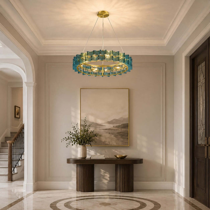 Blue round Orvex chandelier lighting a sunlit entryway with a wood console table