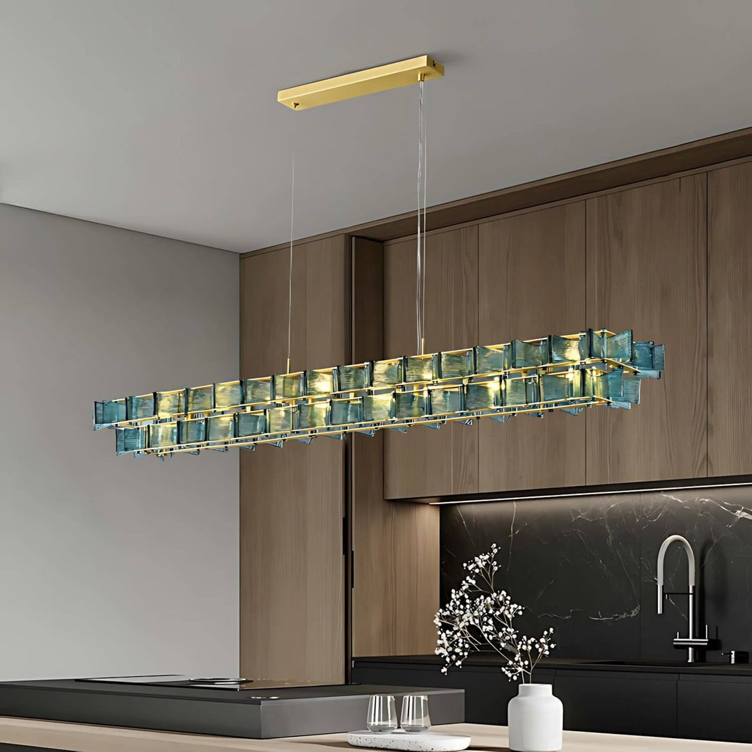 Blue Orvex linear chandelier suspended above an island in a modern dark wood kitchen