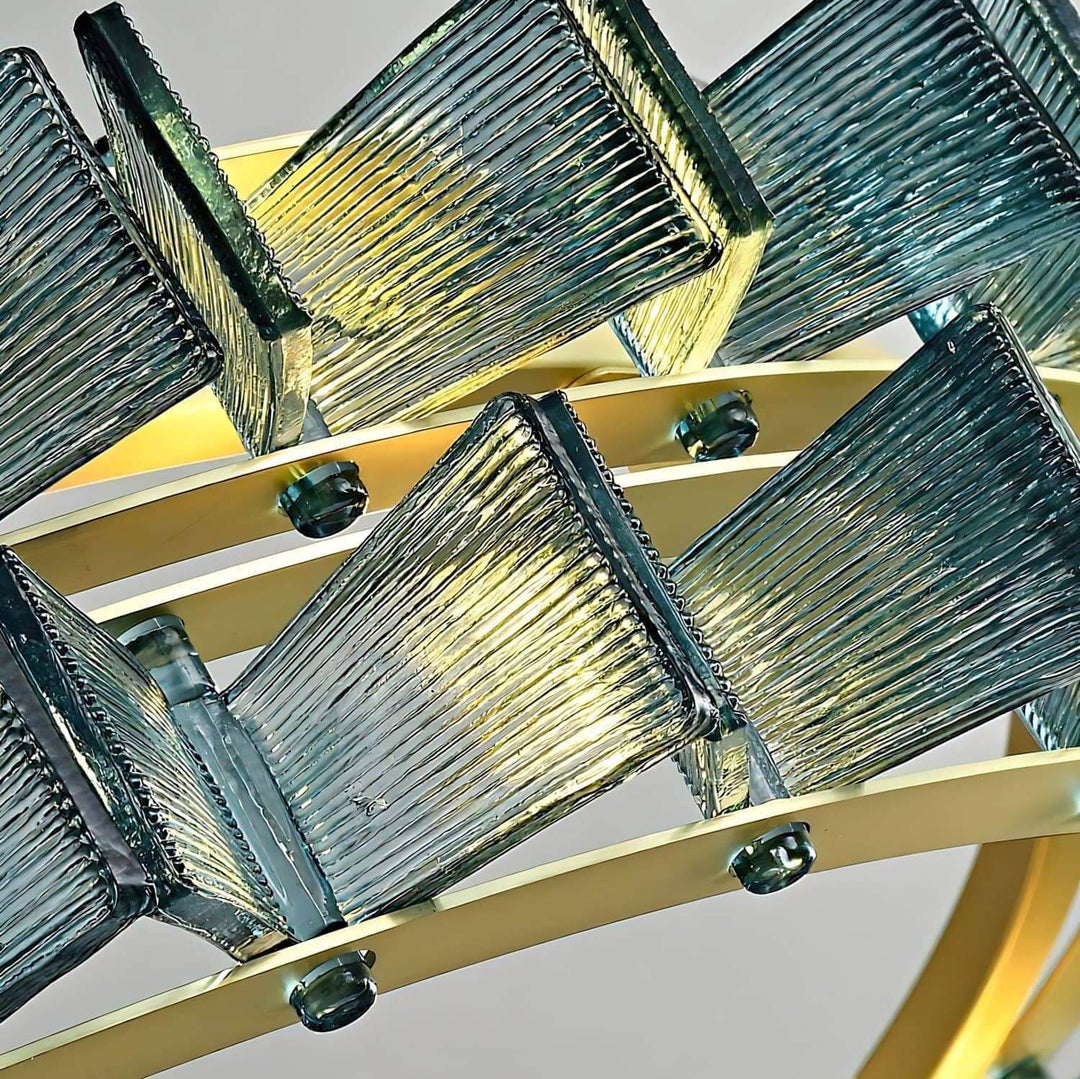 Macro view of blue ribbed glass panels and the brushed gold frame on the Orvex chandelier
