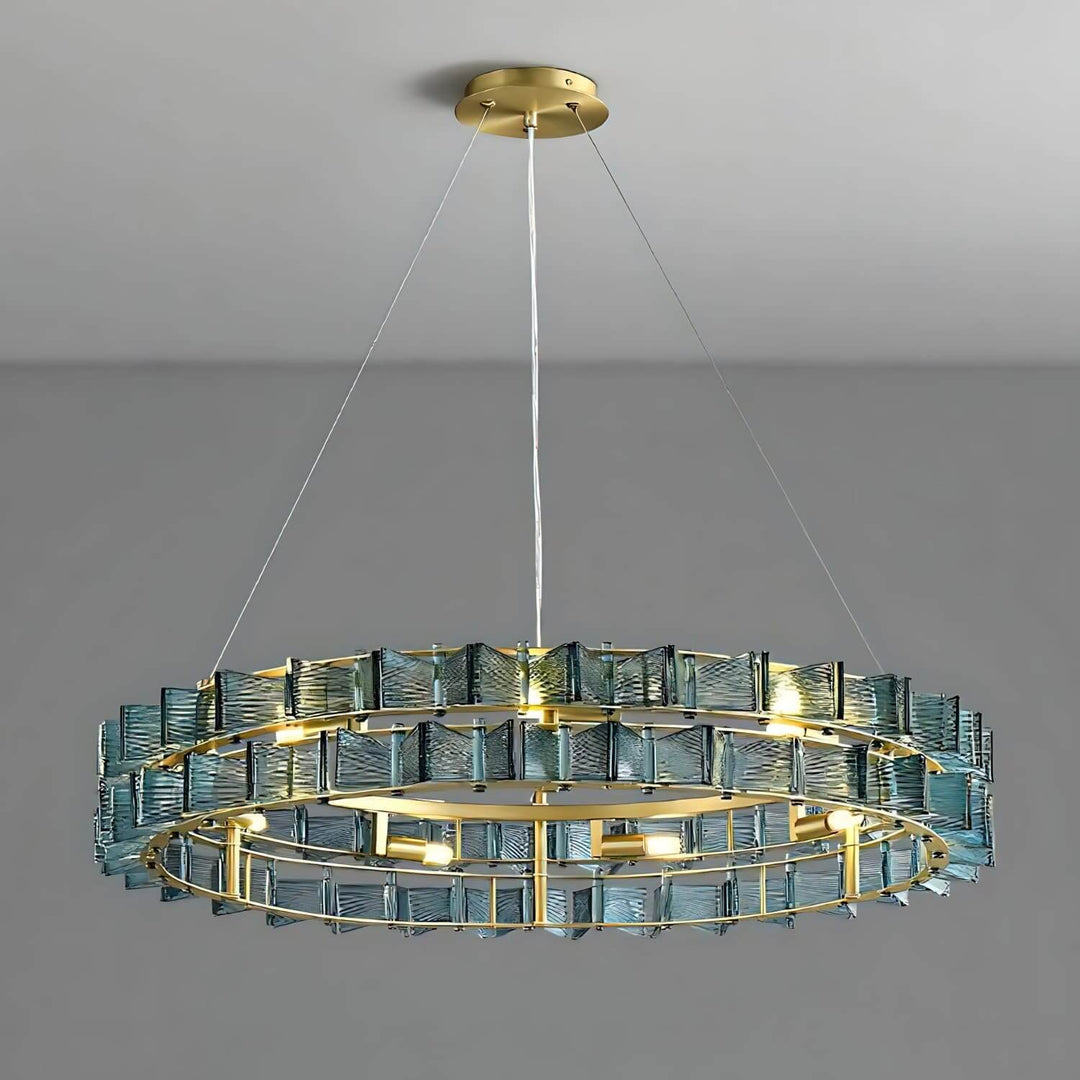 Blue Orvex round chandelier with a brushed gold frame on a gray background