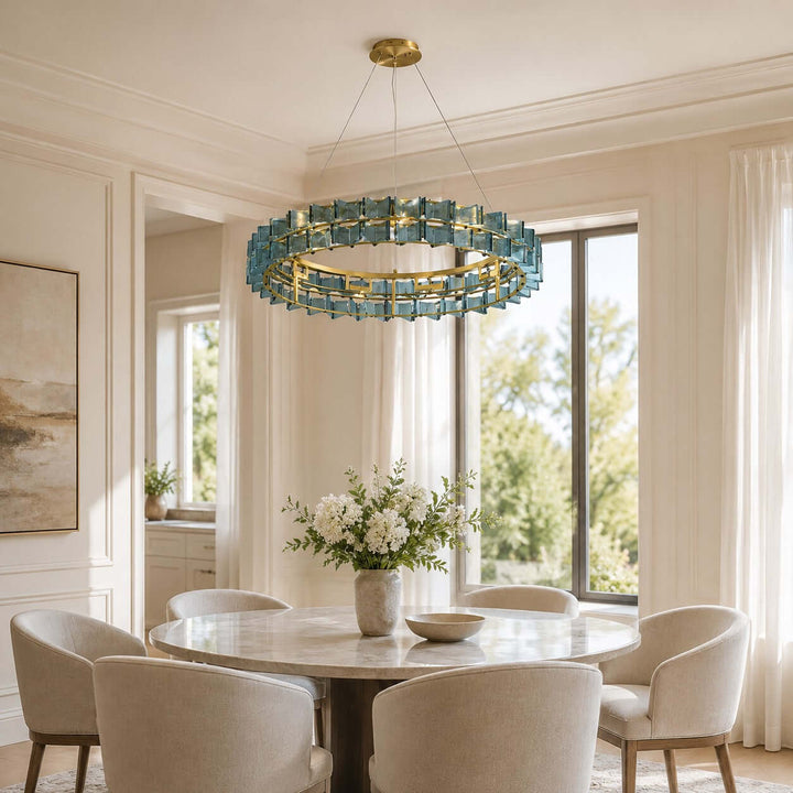 Large blue Orvex dining room chandelier above a round table beside floor-to-ceiling windows