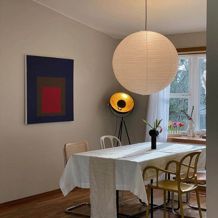 Oversized round rice paper pendant light above a rectangular dining table