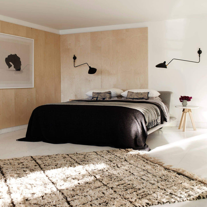 Pair of black adjustable wall-mounted reading lights installed on both sides of a bed