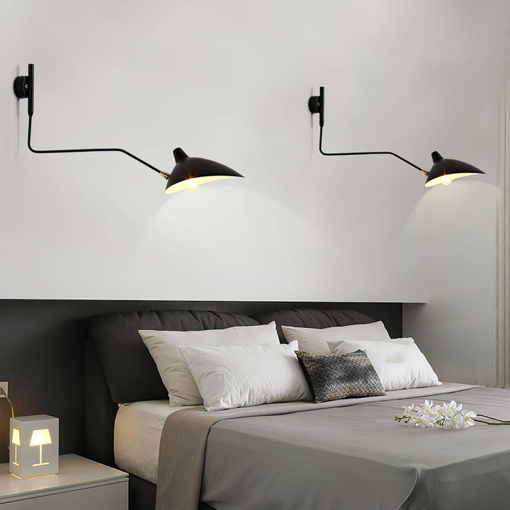 Pair of black one-light swing arm wall sconces mounted above a modern bed