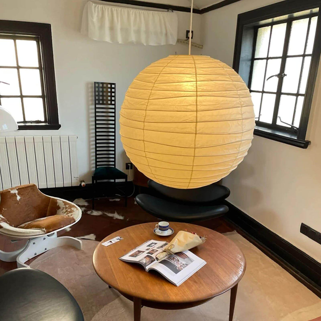 Large paper lantern pendant light above a round wood coffee table in a sitting room.