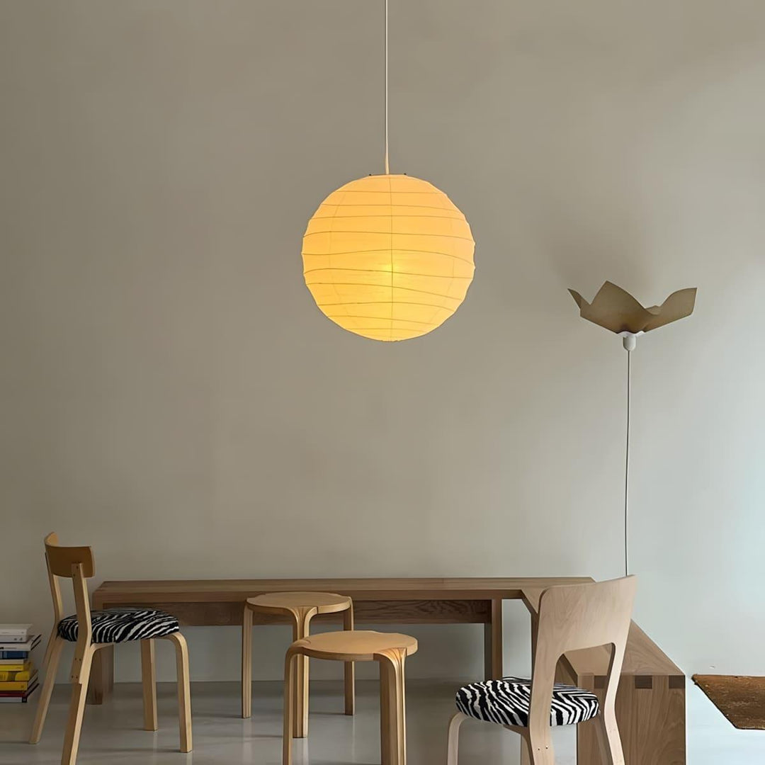 Small paper lantern pendant light above a simple wood dining table and chairs.