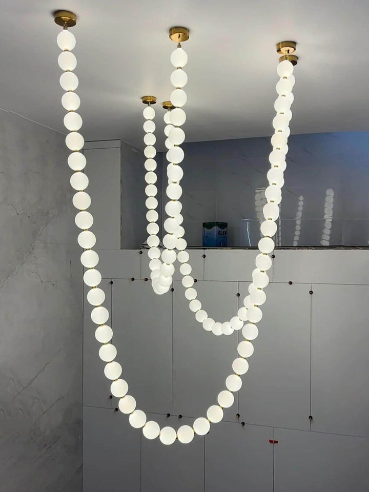 Pearl necklace chandelier with glowing globe strands in a room under installation or renovation.