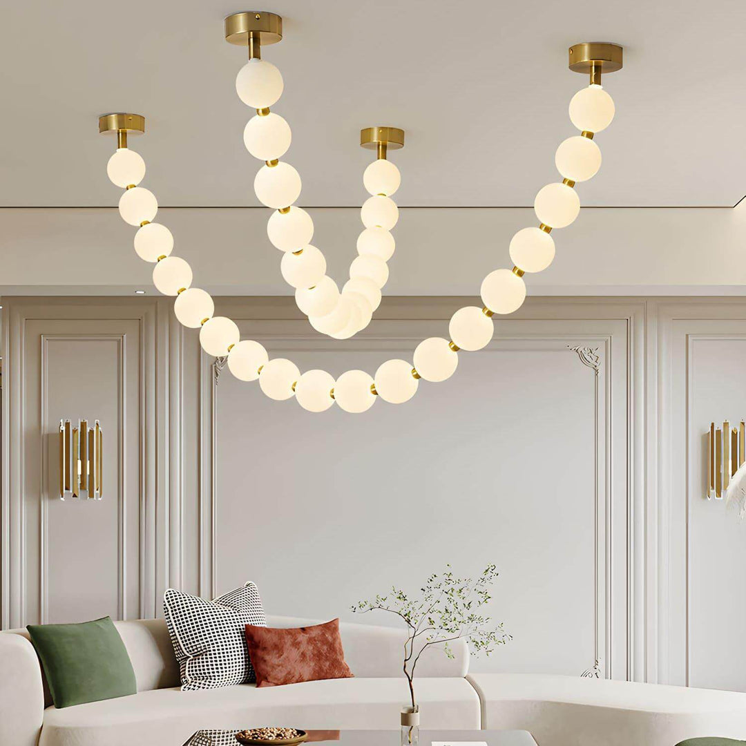 Close living room view of a large pearl necklace chandelier above a curved sofa.