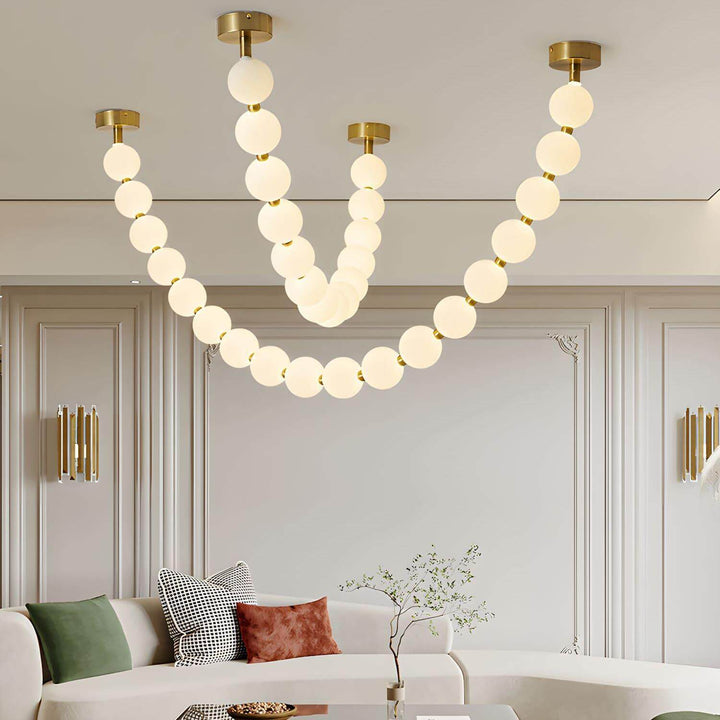 Close living room view of a large pearl necklace chandelier above a curved sofa.