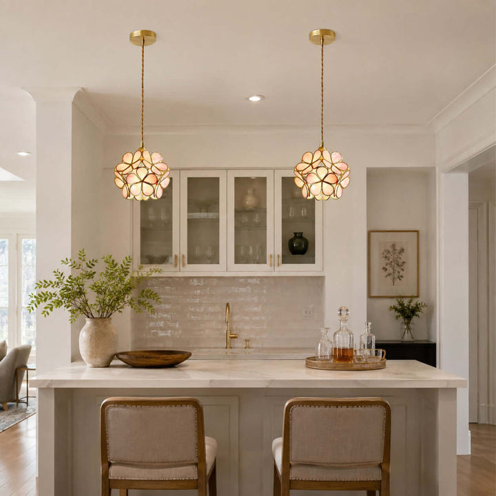 Pair of pink glass petal pendant lights suspended above a white kitchen island