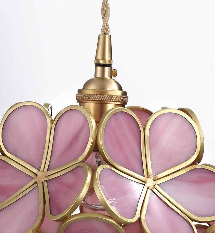 Close-up of pink stained glass petals and antique brass framing on a floral pendant light