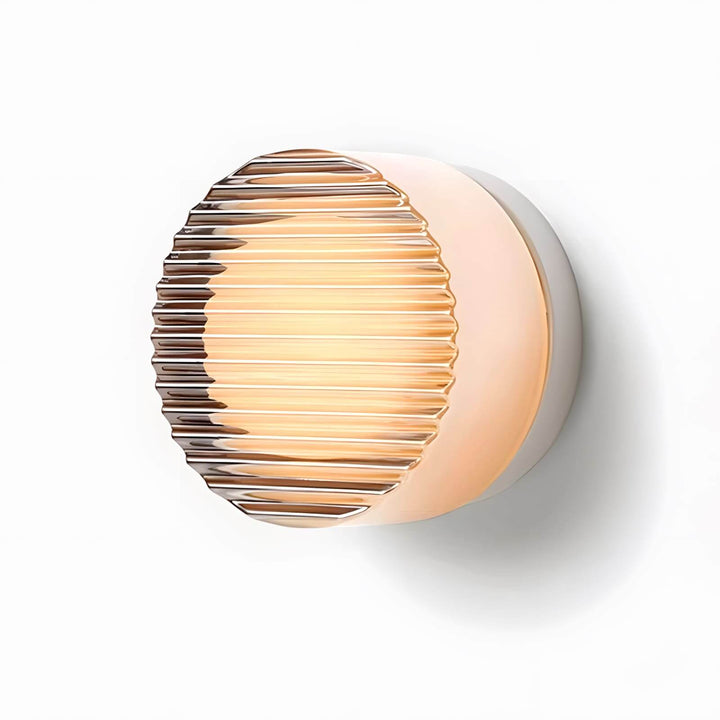 Ribbed amber glass wall sconce lit on a white background.
