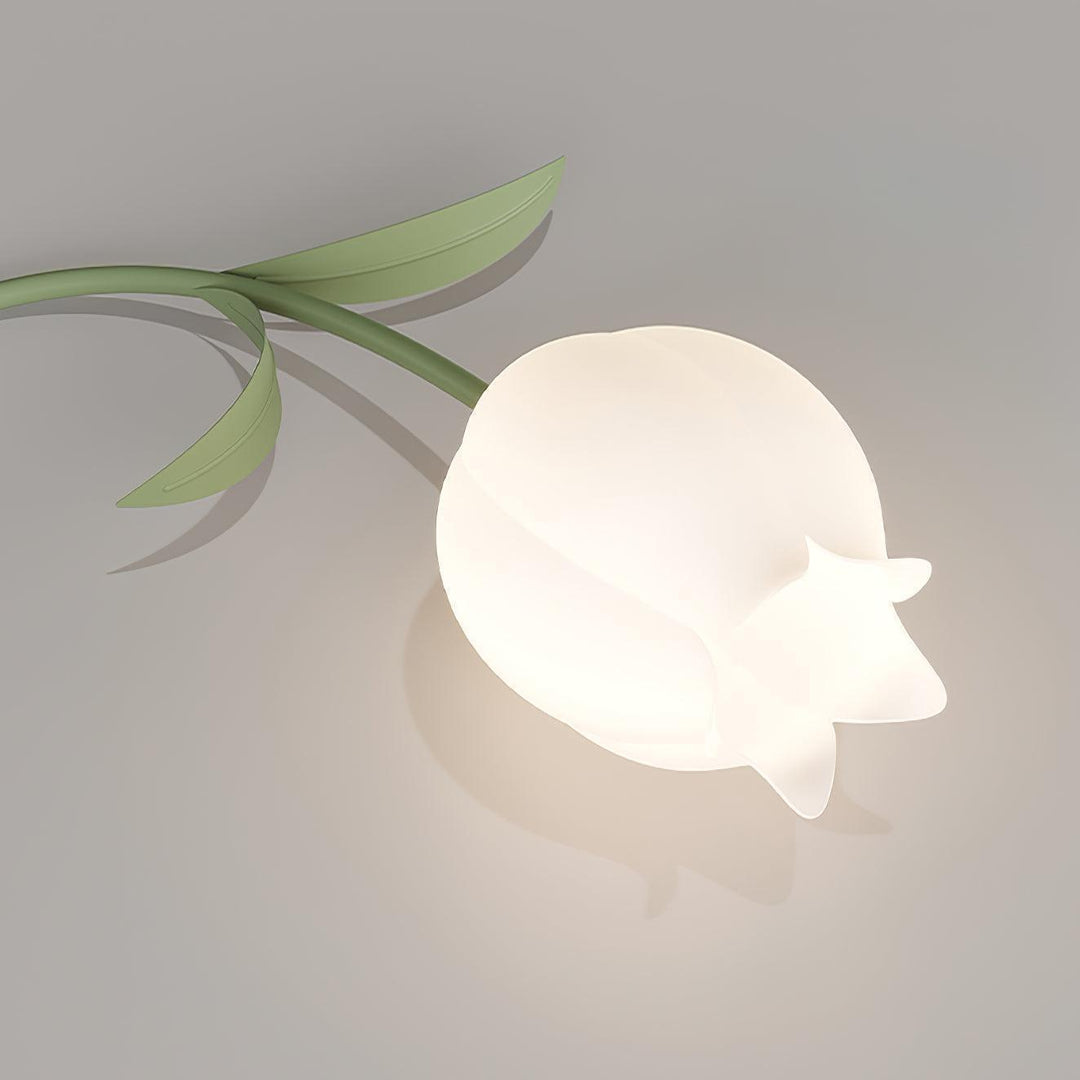 Close-up of a softly glowing cream lily-shaped shade on the Ricko green ceiling light.