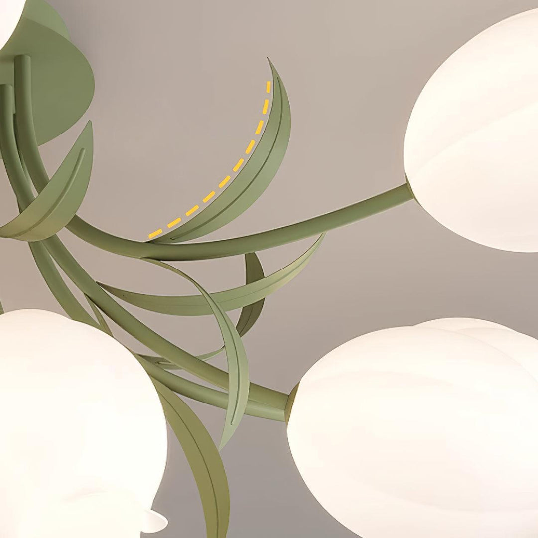 Detail of the Ricko ceiling light’s curved green metal leaves and branching arms between the flower shades.