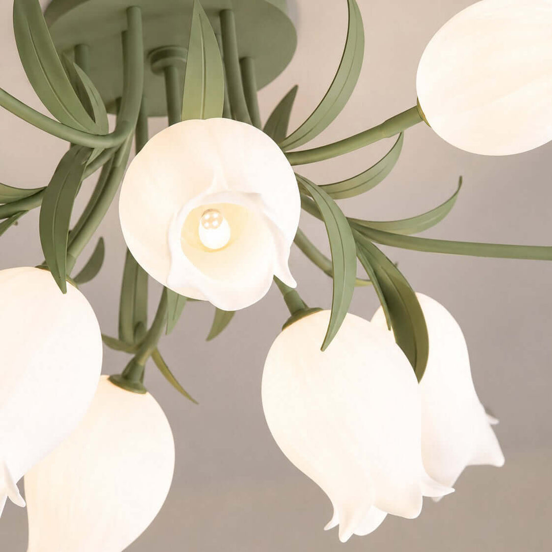 Close-up of the Ricko ceiling light showing its green leafy frame, cream flower shades, and visible bulb.