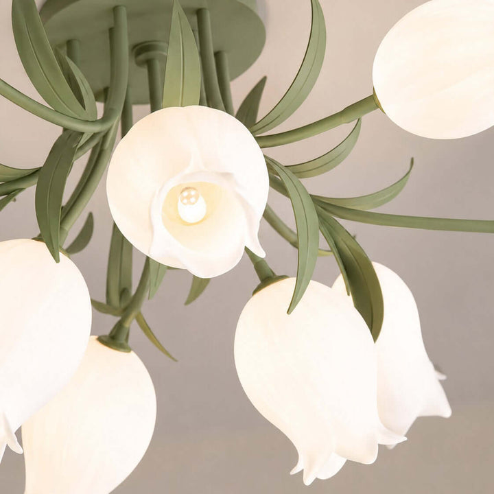 Close-up of the Ricko ceiling light showing its green leafy frame, cream flower shades, and visible bulb.