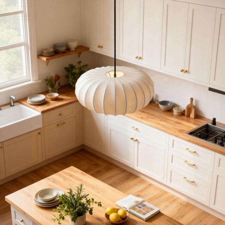 Round white fabric pendant light above a butcher-block island in a bright white kitchen