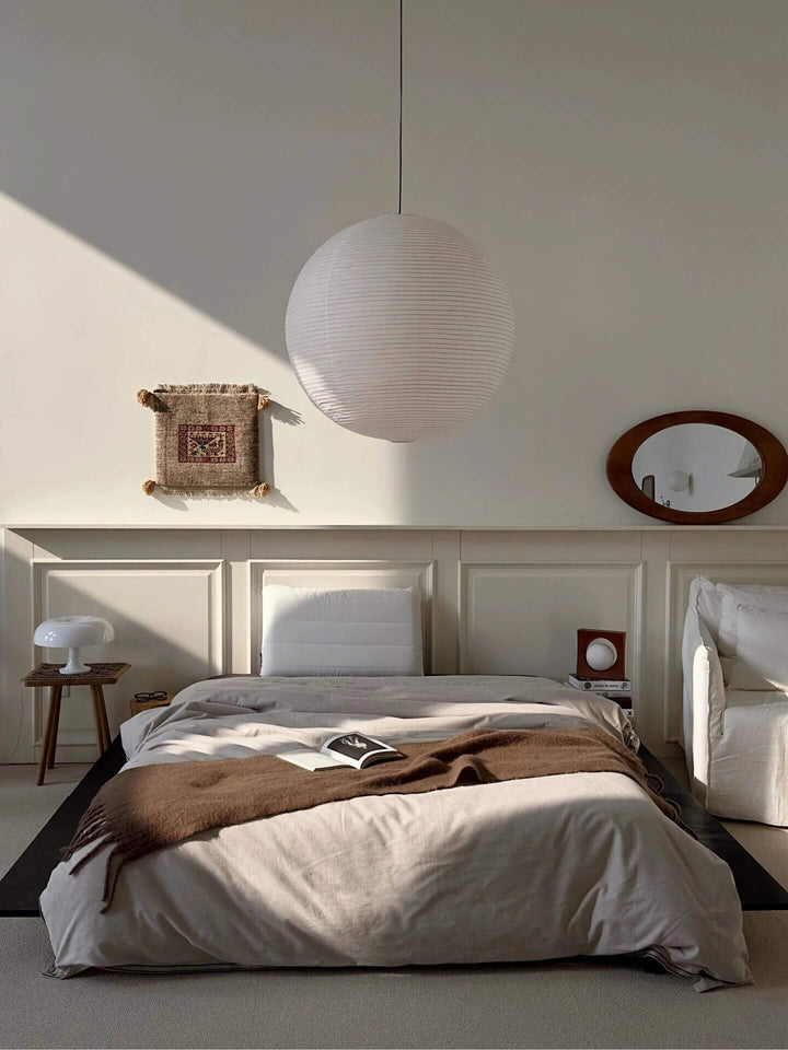 Round white paper lantern pendant above a sunlit neutral bedroom