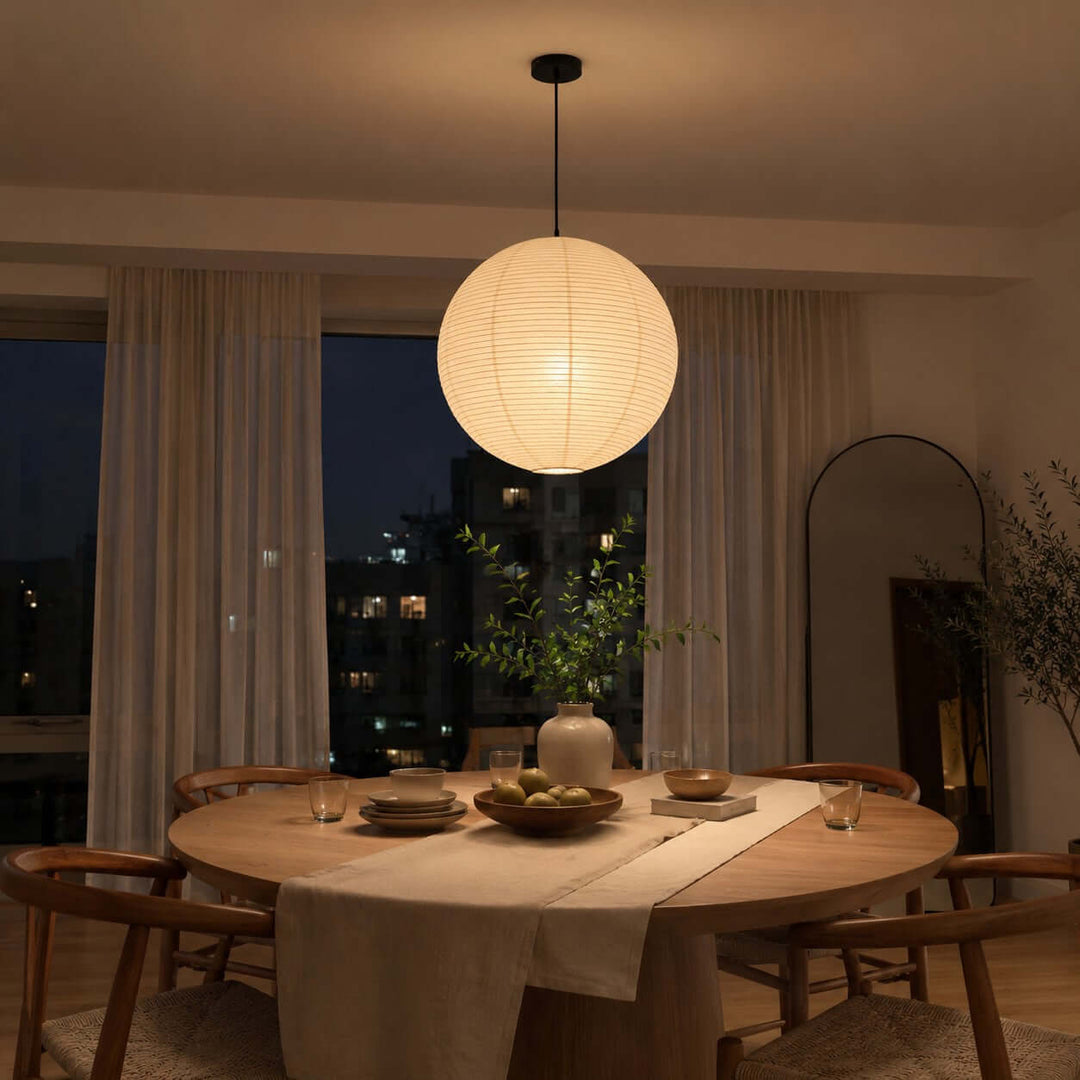 Round paper lantern pendant casting warm light above a dining table at night