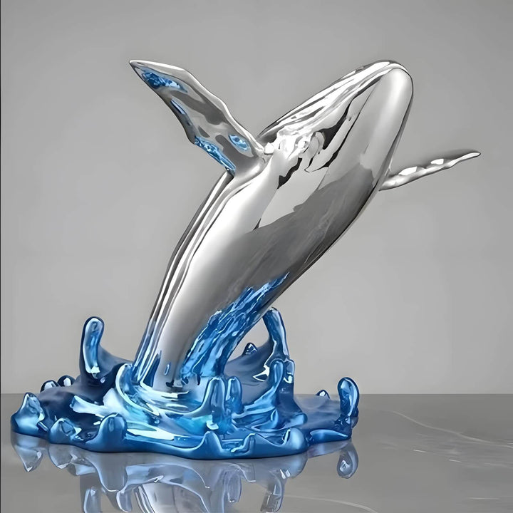 Close-up of the polished silver whale sculpture emerging from a translucent blue resin wave base.