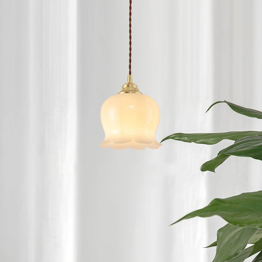 Small hanging light with a warm flower-shaped shade beside green plants and white curtains